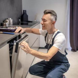 Ein Küchenmonteur von Tischer & Teuber baut eine Spülmaschine ein.